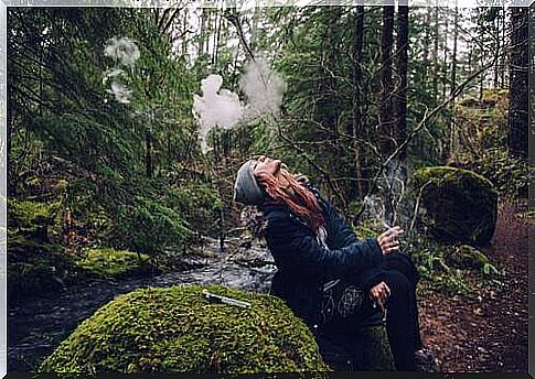 Woman smoking in the forest 