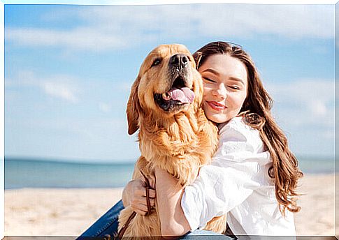 girl hugs dog at the beach